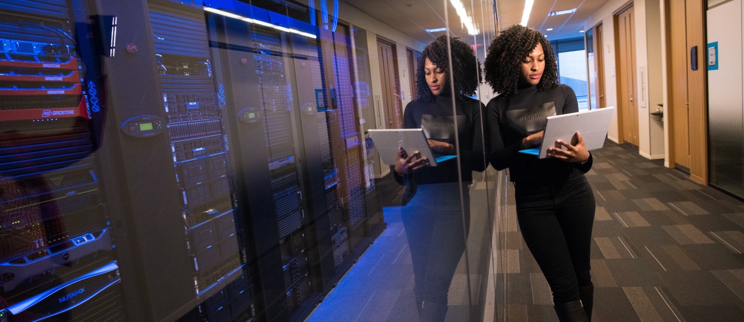 Woman leaning against glass wall containing servers