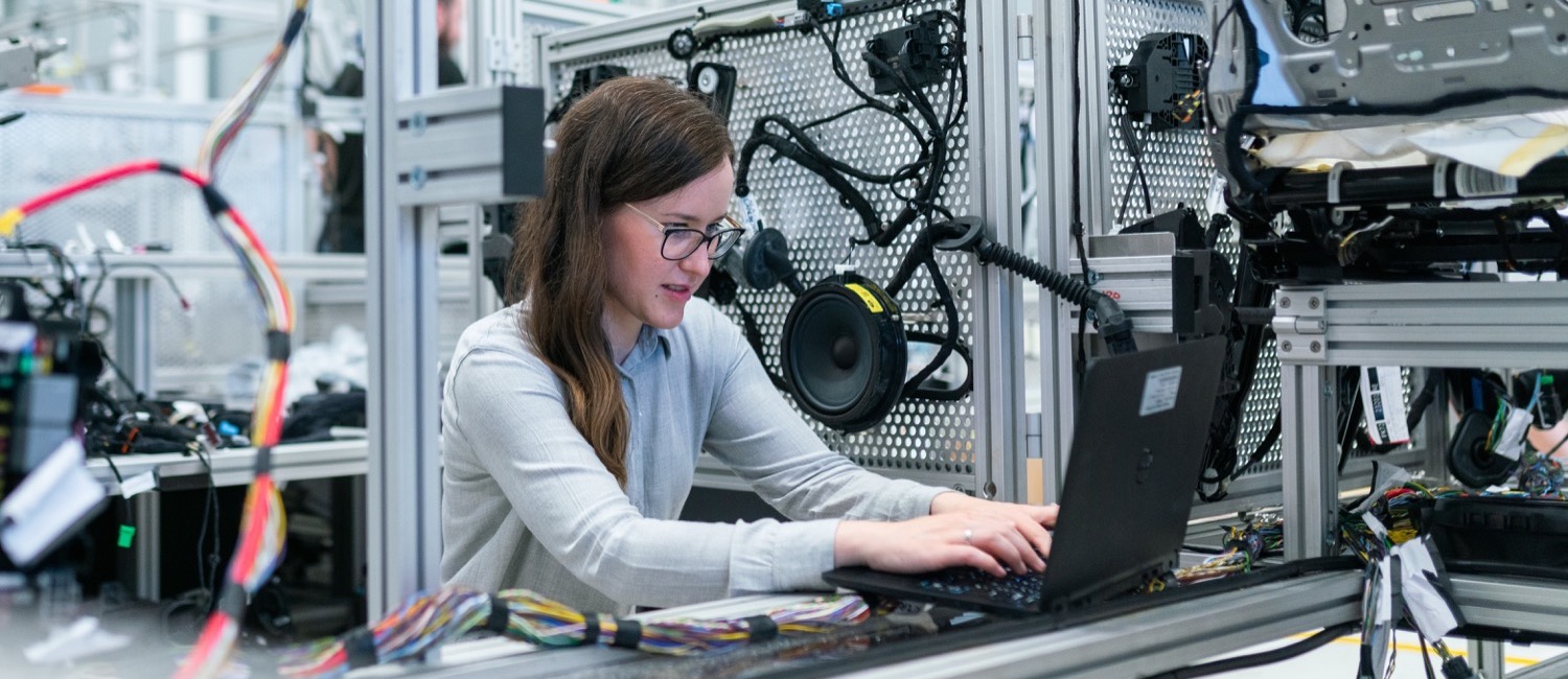 Female electronics engineer working on laptop surrounded by car electronics