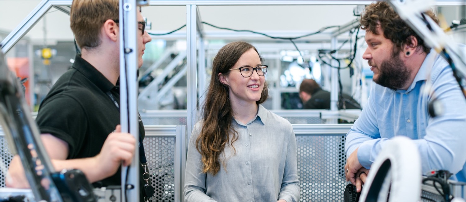 Three electrical engineers talking in production plant